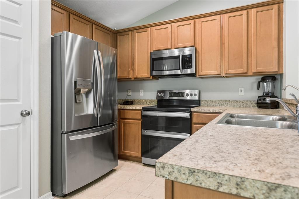 A kitchen features stainless steel appliances, wood cabinets, and speckled laminate countertops — 5701 SWEET WILLIAM TERRACE, LAND O LAKES, FL