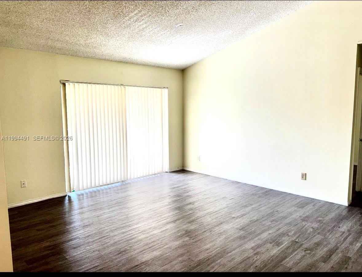 An empty room features light-colored walls, a textured ceiling, and wood-look flooring — 10521 SW 158th Ct # 303, Miami FL 33196, MIAMI, FL