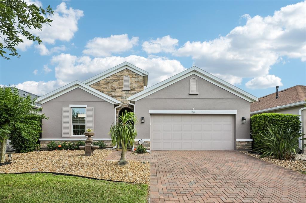 A single-story house with a stone facade, gray stucco, and a brick paver driveway — 508 NARROW VIEW LANE, GROVELAND, FL
