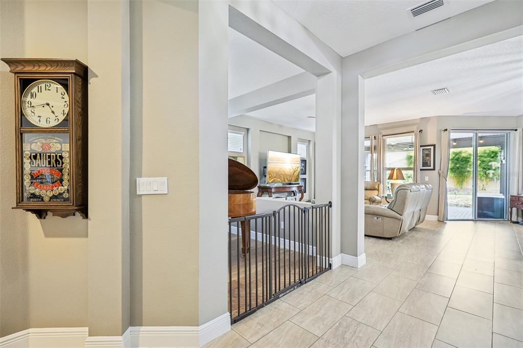 A hallway with tile flooring leads to a living area featuring a baby grand piano — 508 NARROW VIEW LANE, GROVELAND, FL