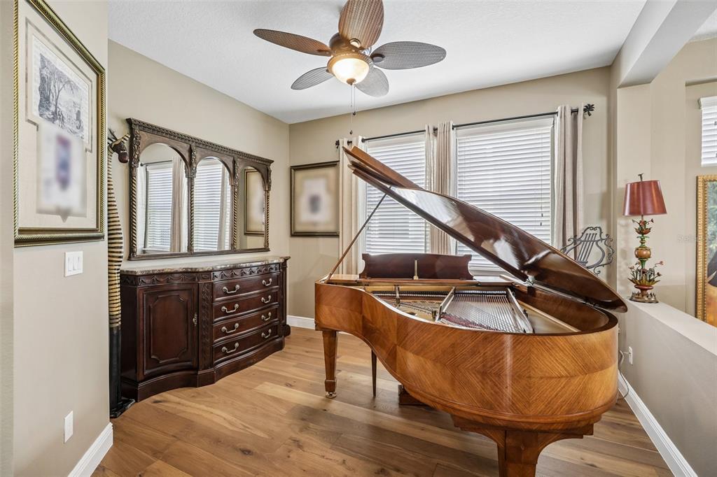 A grand piano sits in a room with wood floors, a ceiling fan, and a dresser — 508 NARROW VIEW LANE, GROVELAND, FL