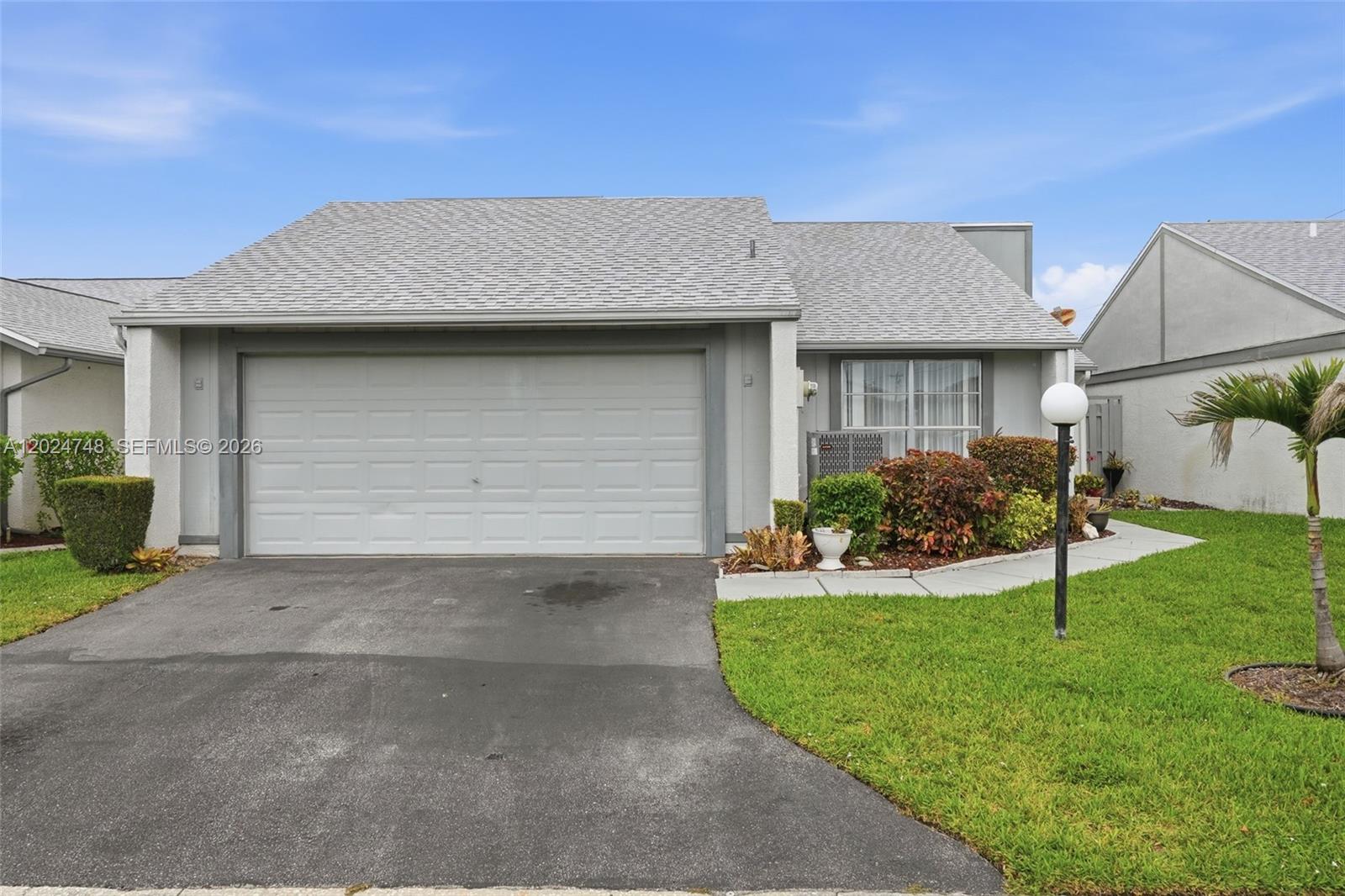 A single-story house features a gray garage door, a shingled roof, and a front lawn — 18441 Orangecrest CT, Lehigh Acres FL 33936, LEHIGH ACRES, FL