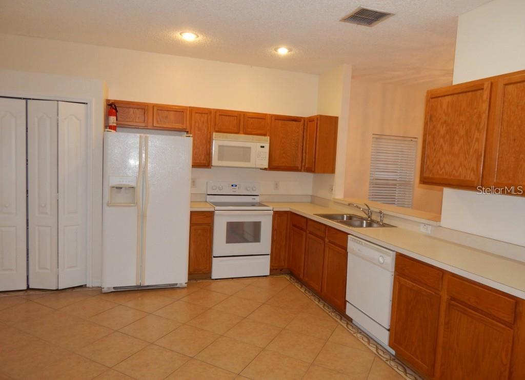 A kitchen with wood cabinets, white appliances, and light-colored tile flooring — 4434 WATERSIDE POINTE CIRCLE, ORLANDO, FL