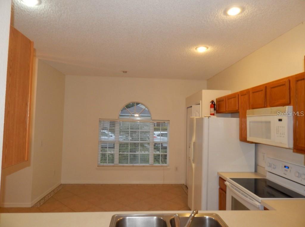 A kitchen with wood cabinets, white appliances, and a dining area with an arched window — 4434 WATERSIDE POINTE CIRCLE, ORLANDO, FL