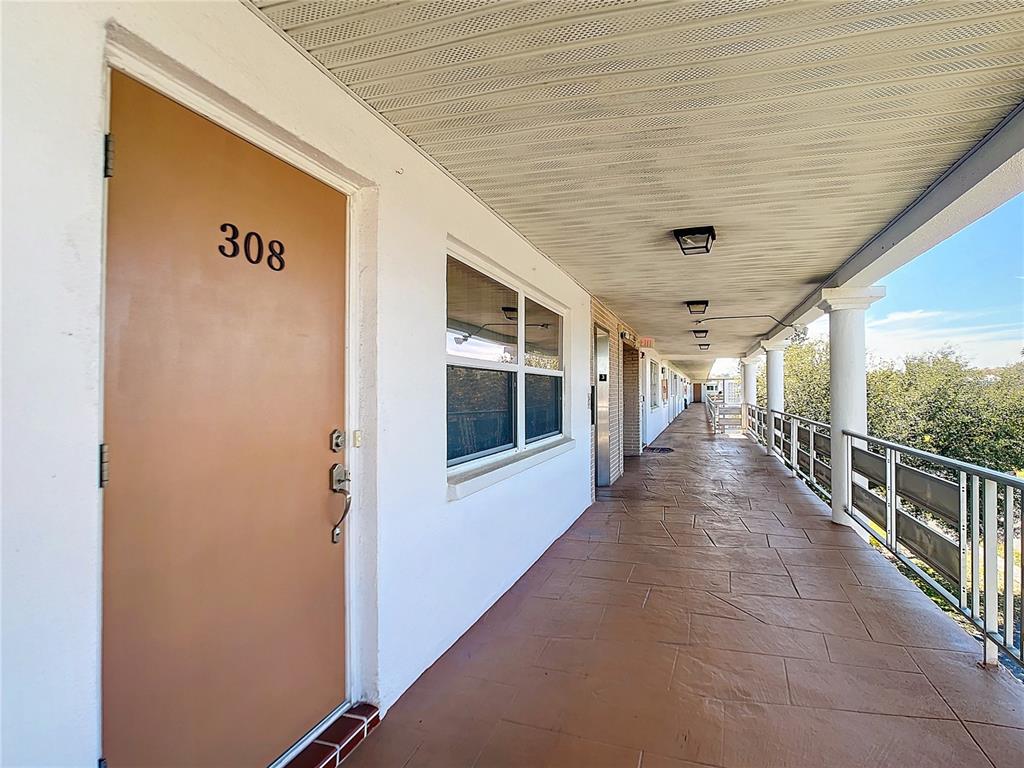 An exterior walkway leads past apartment door 308 with a tiled floor and metal railing — 6015 19TH STREET N UNIT 308, ST PETERSBURG, FL