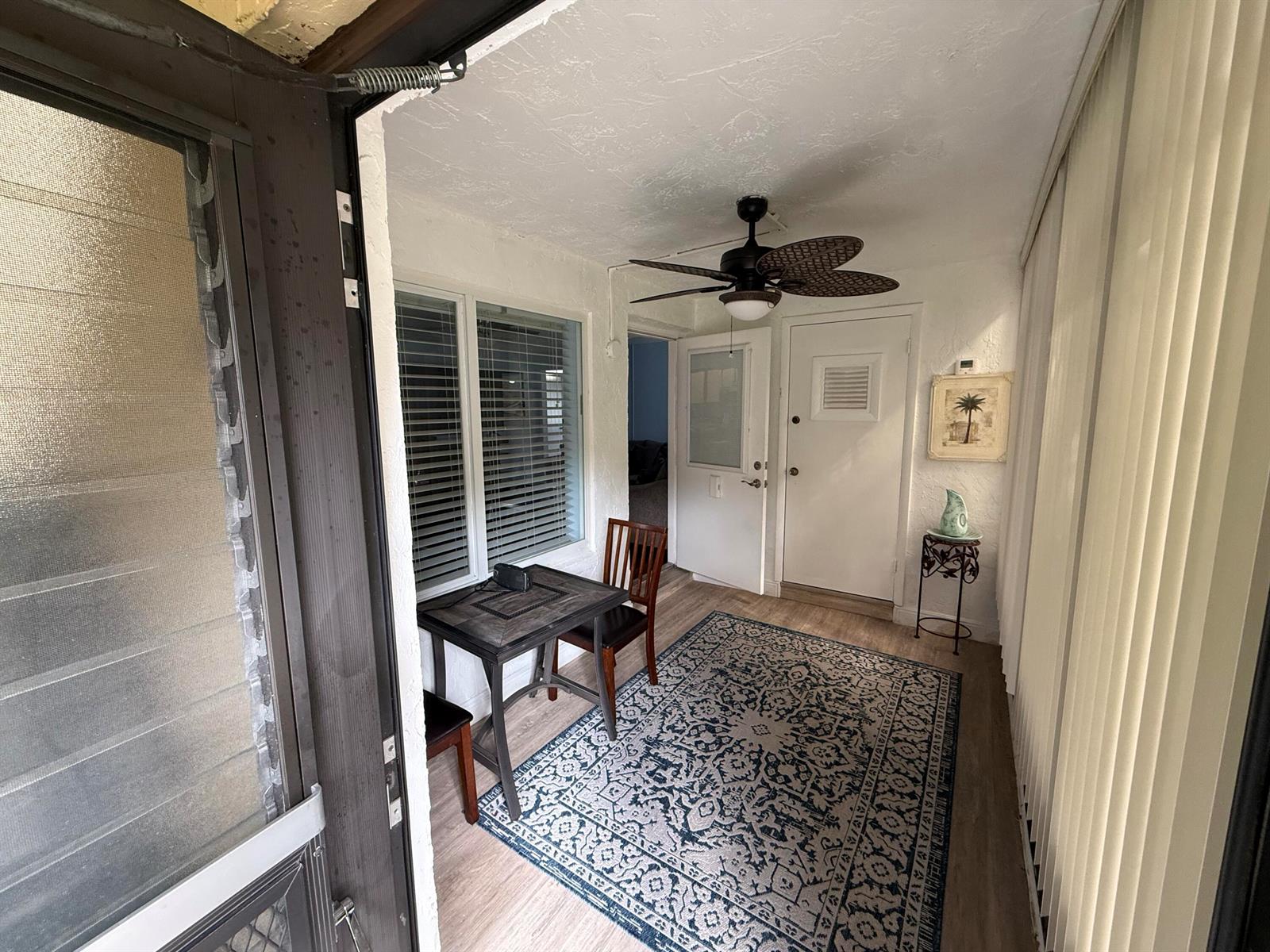 A sunroom features a ceiling fan, a small dining set, and a patterned area rug — 301 Pine Ridge Circle # 1, FL 33463, FL