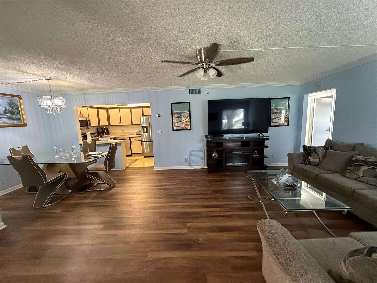 An open-concept living and dining area features light blue walls, wood-look flooring, and a ceiling fan — 301 Pine Ridge Circle # 1, FL 33463, FL