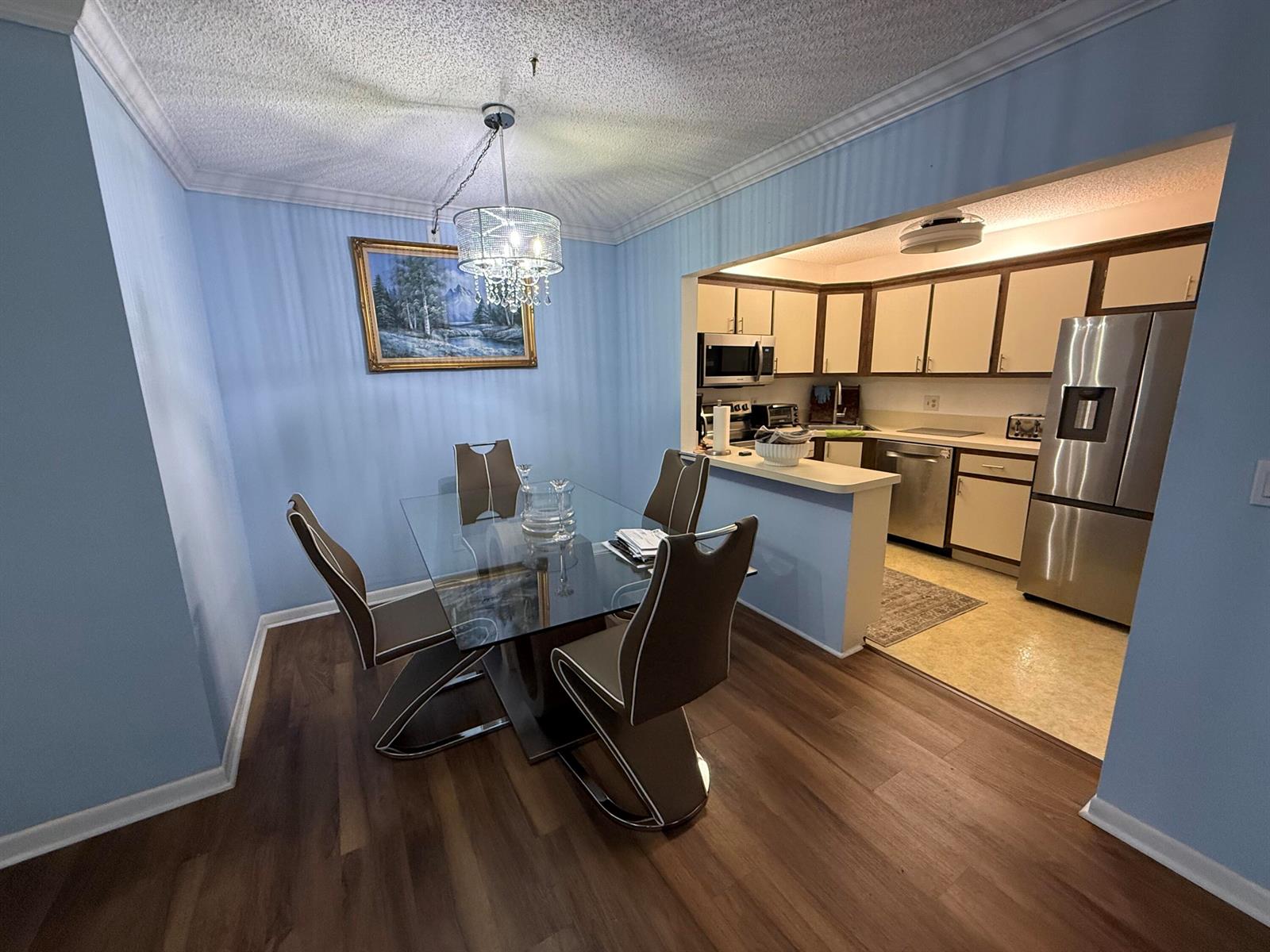 A dining area with a glass table and blue walls opens into a kitchen with appliances — 301 Pine Ridge Circle # 1, FL 33463, FL