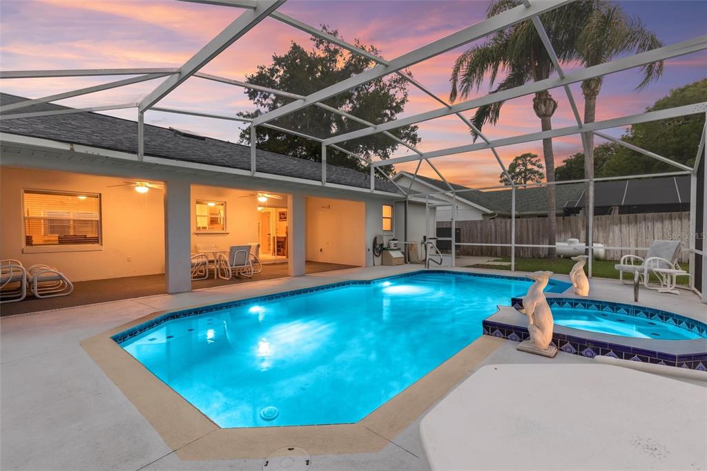 A screened-in swimming pool and spa area with a covered patio at sunset — 1179 PEACHTREE ROAD, DAYTONA BEACH, FL