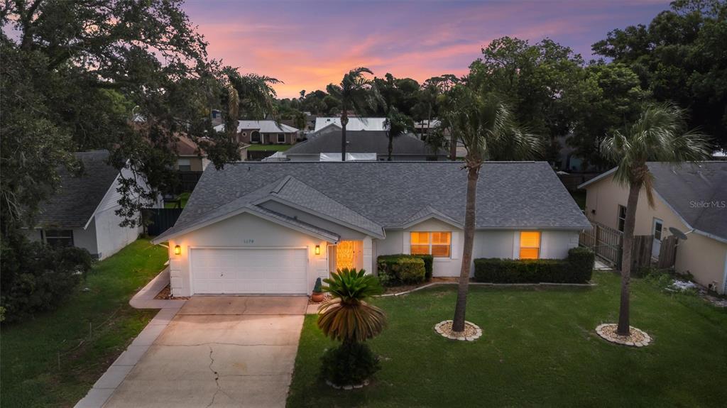 An exterior view of a single-story house with a two-car garage and palm trees — 1179 PEACHTREE ROAD, DAYTONA BEACH, FL