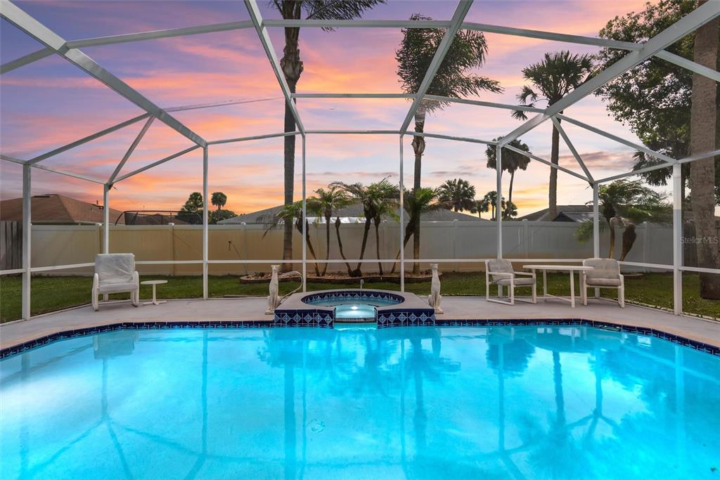A swimming pool and spa are enclosed by a screened lanai at sunset — 1179 PEACHTREE ROAD, DAYTONA BEACH, FL