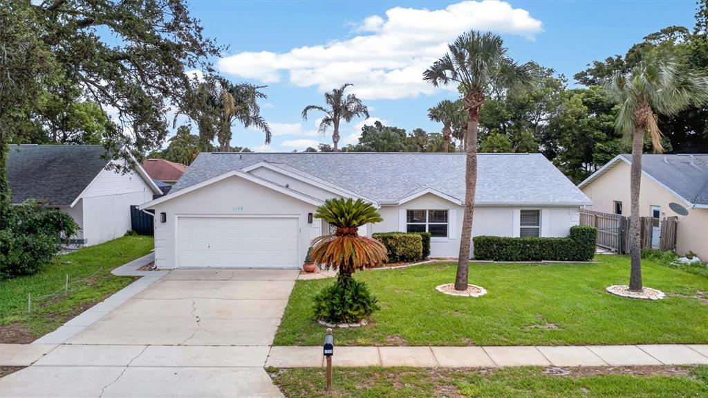 A single-story white house with a two-car garage, palm trees, and a green lawn — 1179 PEACHTREE ROAD, DAYTONA BEACH, FL