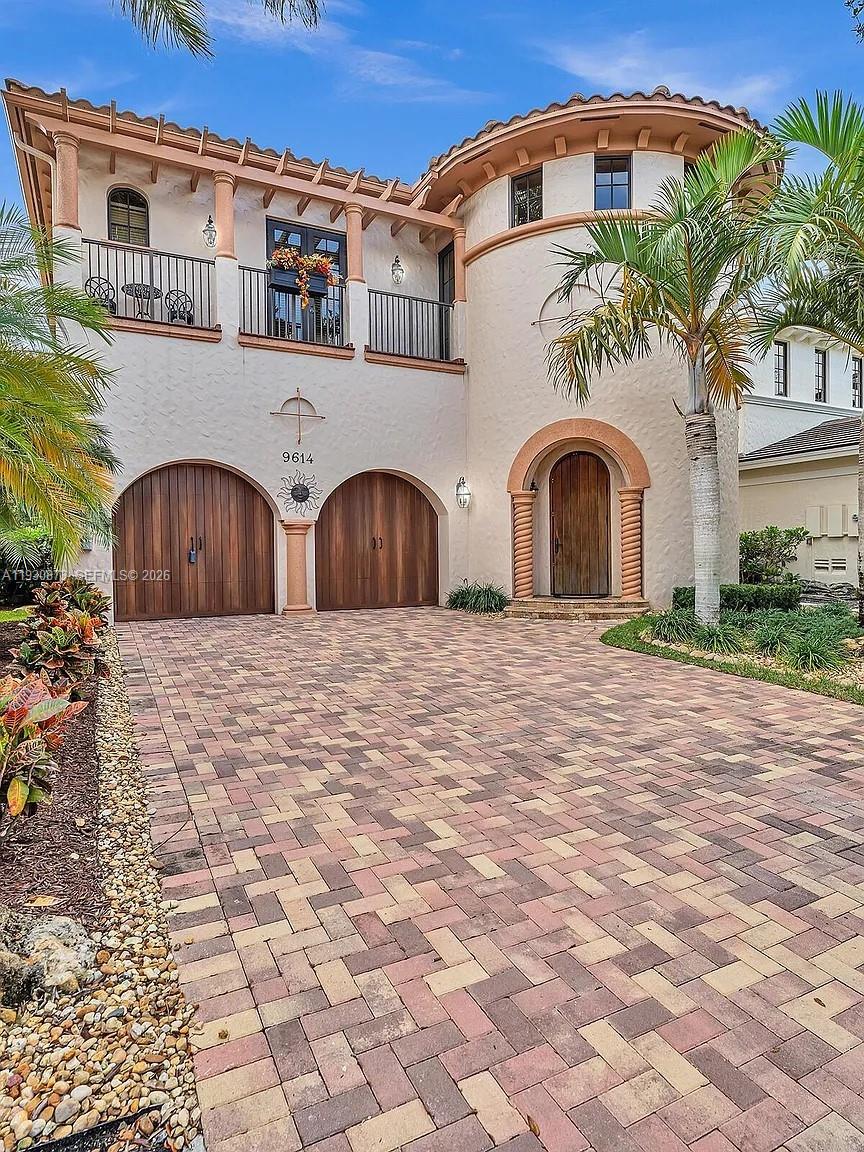A two-story Mediterranean-style house features a paved driveway, arched garage doors, and a rounded entryway — 9614 Kenley Ct, Parkland FL 33076, PARKLAND, FL