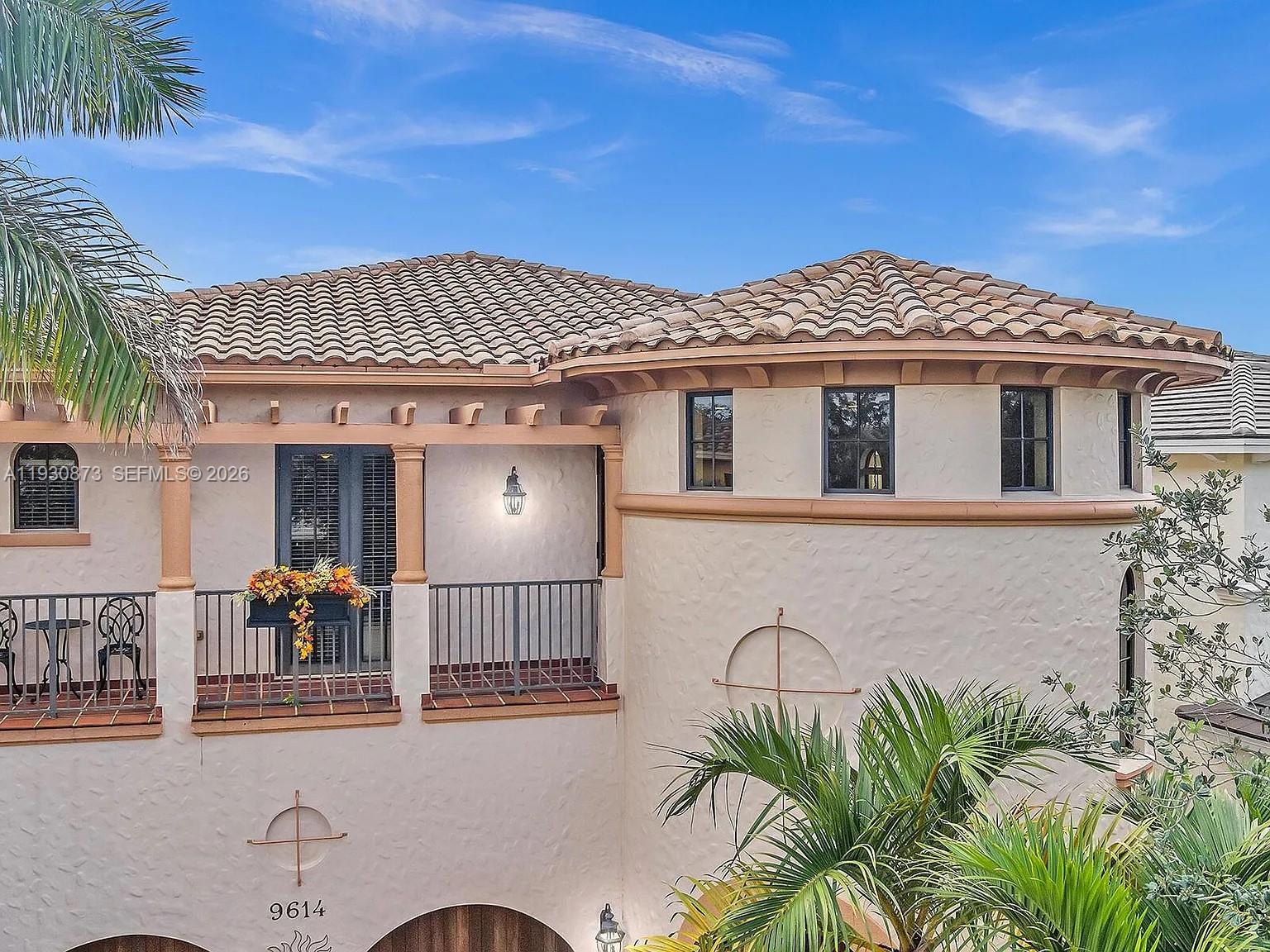 A two-story stucco home features a curved wall, a balcony, and a tiled roof — 9614 Kenley Ct, Parkland FL 33076, PARKLAND, FL