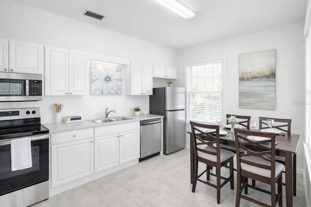 A kitchen with white cabinets, stainless steel appliances, and a small dining table — 501 S MAGNOLIA AVENUE UNIT 3, TAMPA, FL
