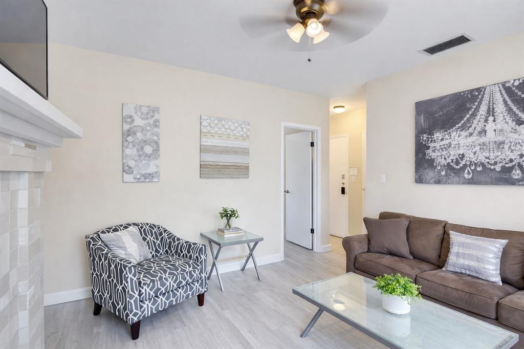 A living room features a patterned armchair, brown sofa, glass coffee table, and ceiling fan — 501 S MAGNOLIA AVENUE UNIT 3, TAMPA, FL