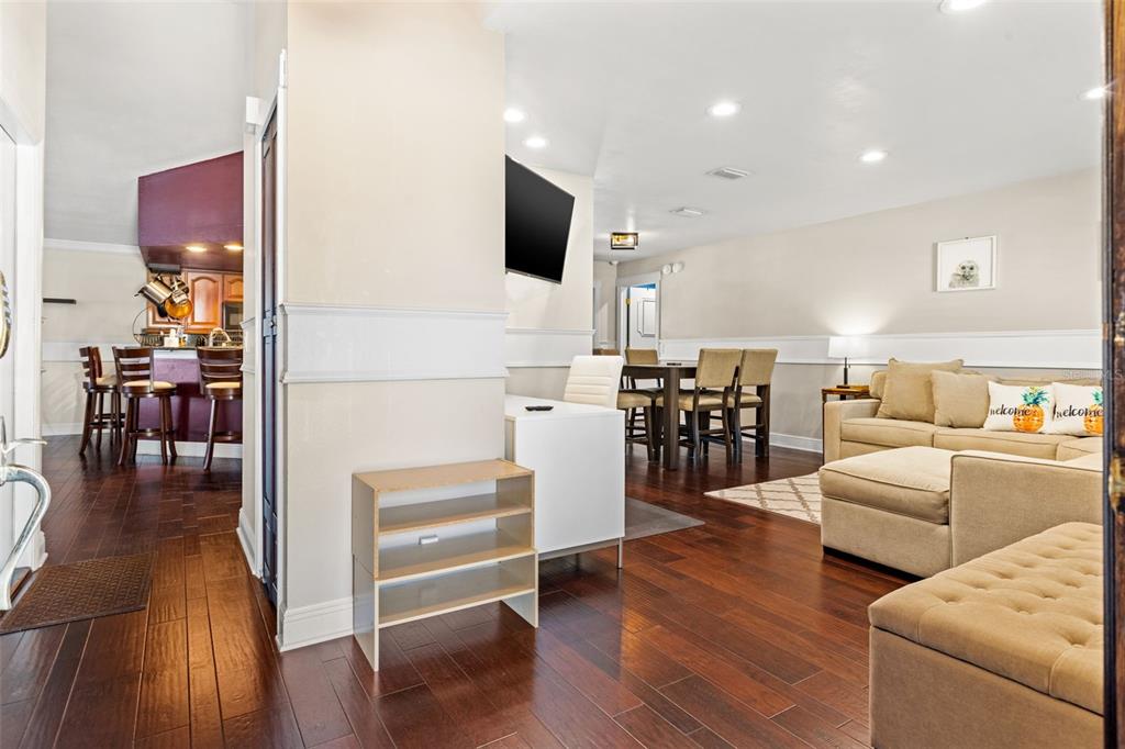 A living room with hardwood floors, a sectional sofa, a dining area, and a kitchen — 6701 LEEWARD ISLE WAY, TAMPA, FL