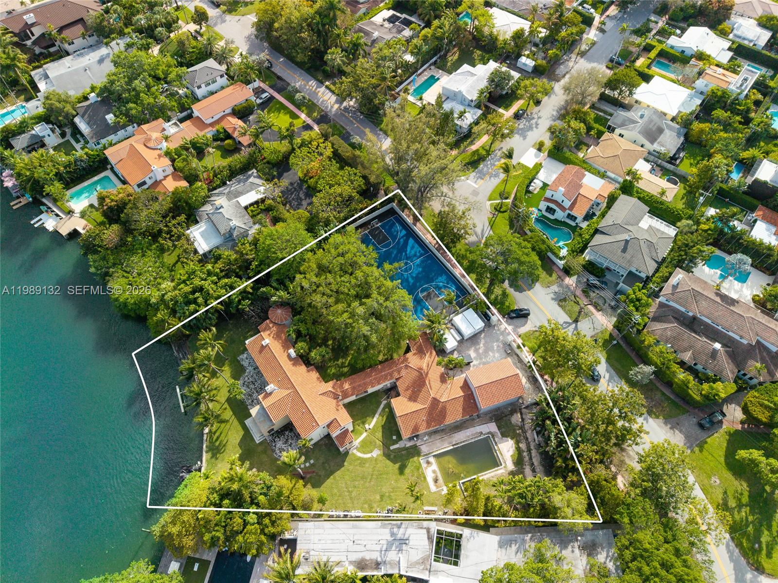 An aerial view shows a waterfront property with a house, swimming pool, and basketball court — 5005 Lakeview Dr, Miami Beach FL 33140, MIAMI BEACH, FL