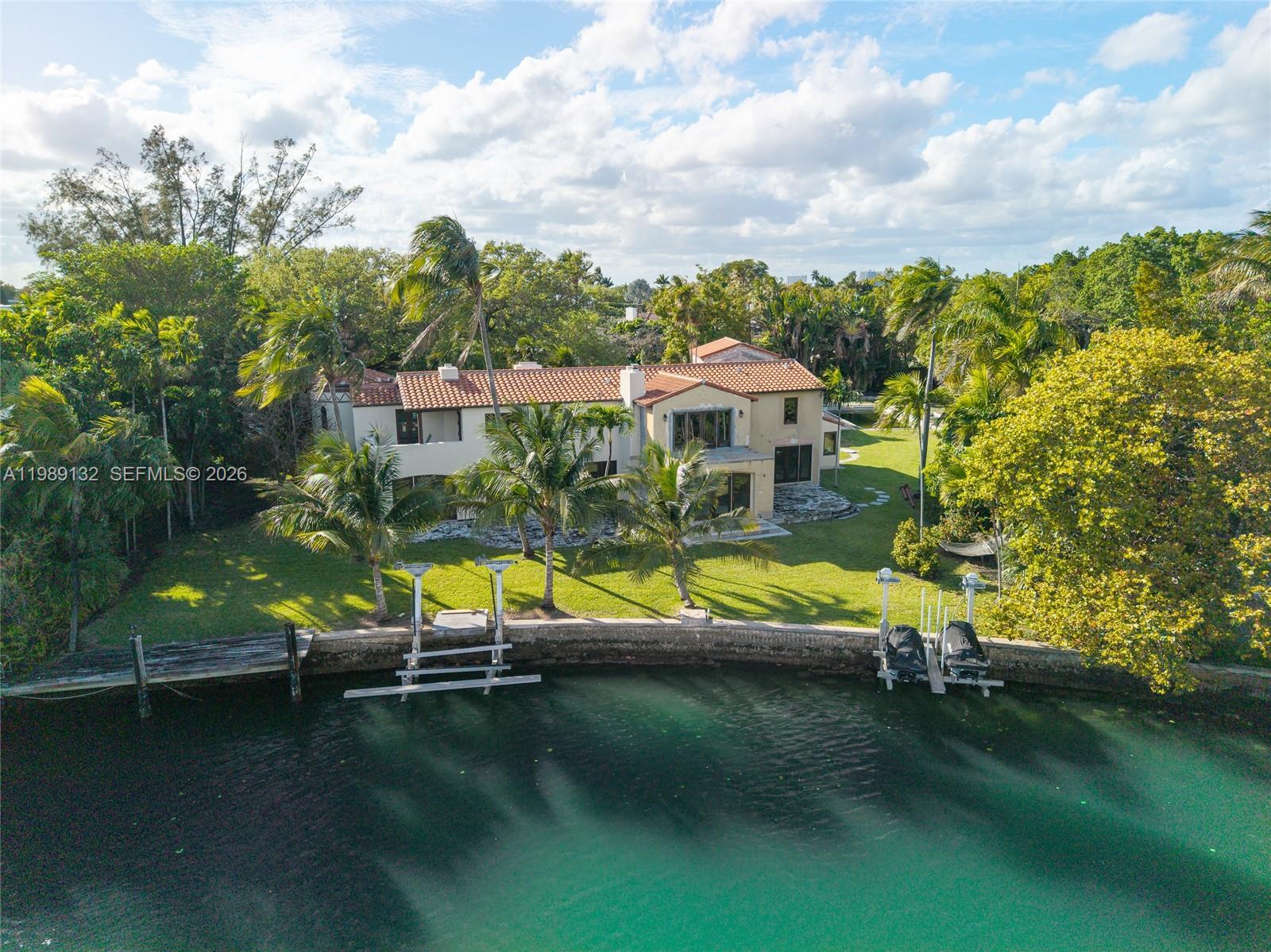 An aerial view shows a two-story house with a tile roof, lawn, and waterfront dock — 5005 Lakeview Dr, Miami Beach FL 33140, MIAMI BEACH, FL