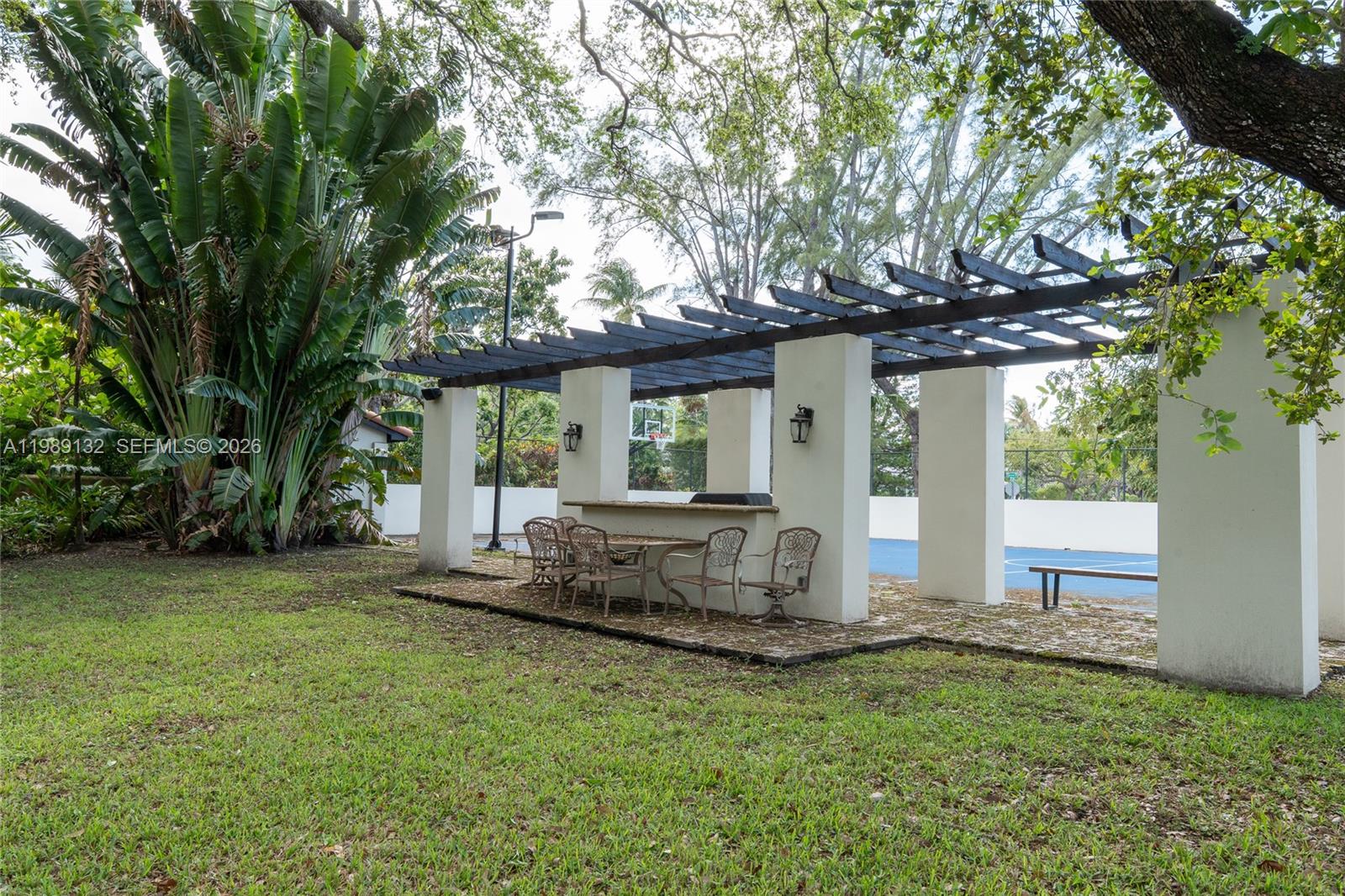 An outdoor patio area features a pergola, a built-in bar, and metal chairs — 5005 Lakeview Dr, Miami Beach FL 33140, MIAMI BEACH, FL