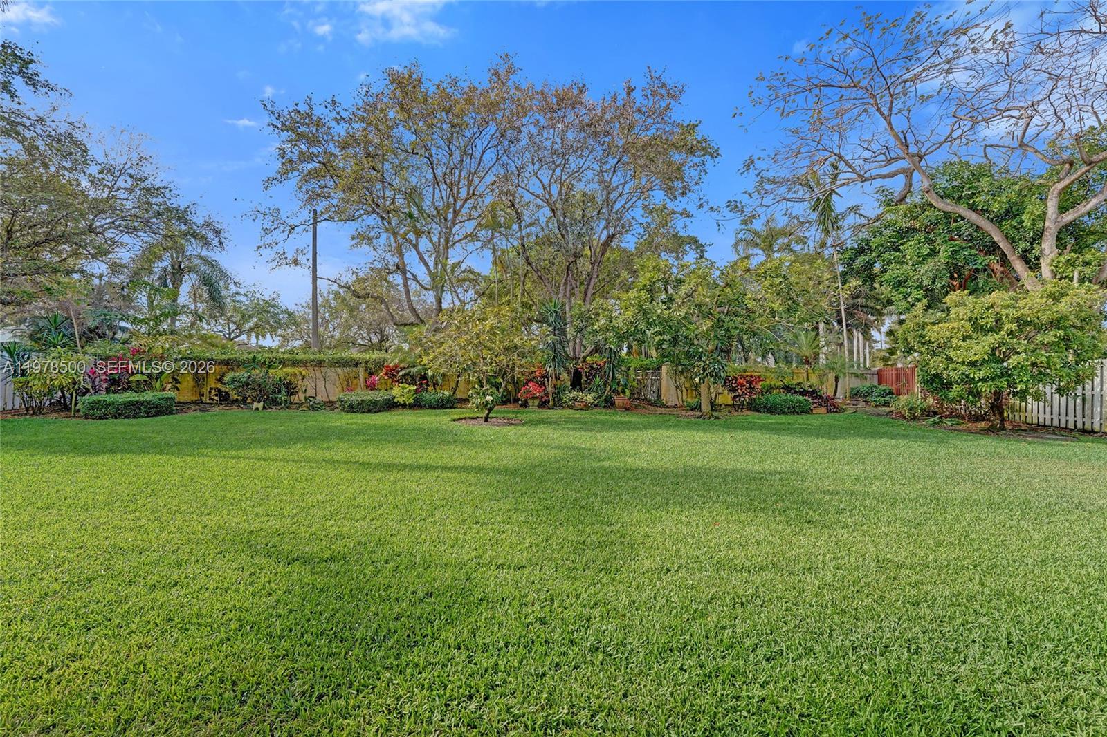 A large, grassy backyard features mature trees, lush landscaping, and a perimeter fence — 14686 SW 35th Ct, Miramar FL 33027, MIRAMAR, FL