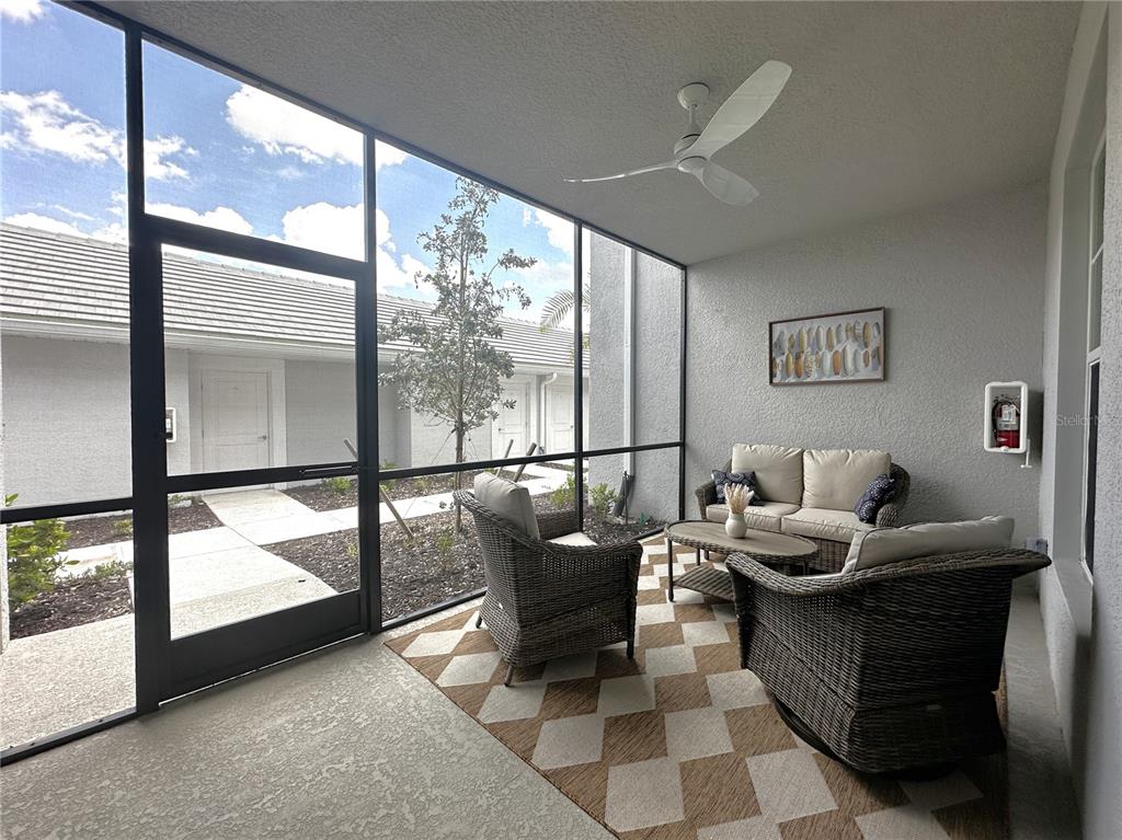 A screened-in patio features wicker furniture, a patterned rug, and a ceiling fan — 14221 HERITAGE LANDING BOULEVARD UNIT 2018, PUNTA GORDA, FL