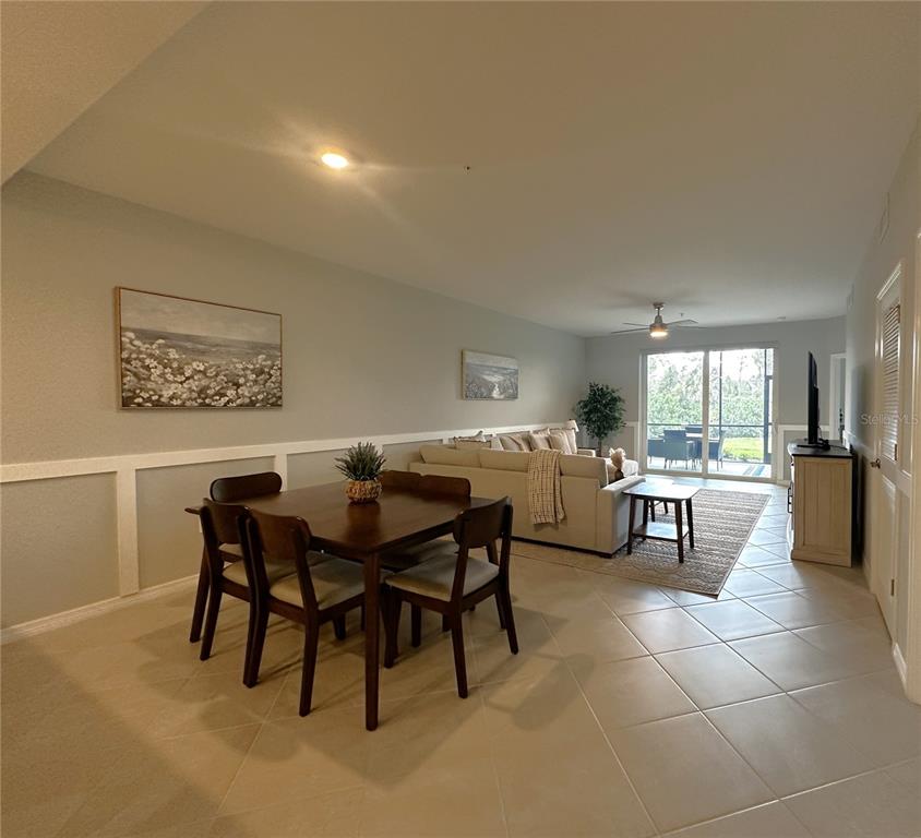 An open-concept living and dining area features tile flooring, a beige sofa, and a wooden table — 14221 HERITAGE LANDING BOULEVARD UNIT 2018, PUNTA GORDA, FL