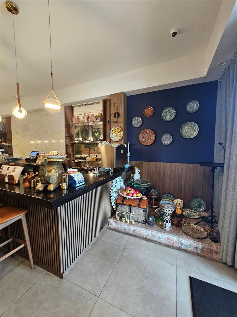 A kitchen area features a dark countertop, slatted wood cabinetry, and a blue accent wall — 2995 NE 163rd St, North Miami Beach FL 33160, NORTH MIAMI BEACH, FL