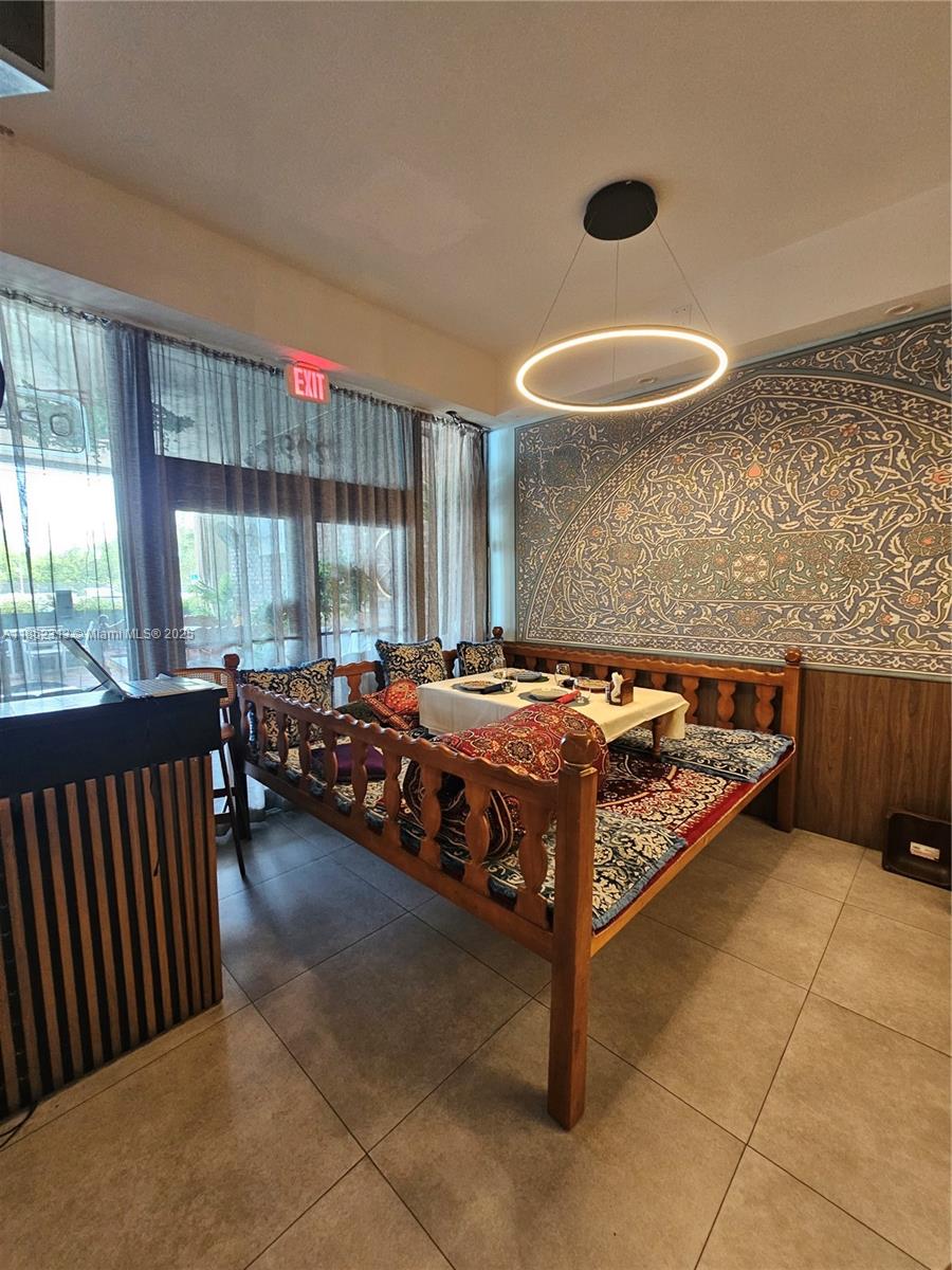 A dining area features a low wooden platform with cushions and a modern ring light — 2995 NE 163rd St, North Miami Beach FL 33160, NORTH MIAMI BEACH, FL