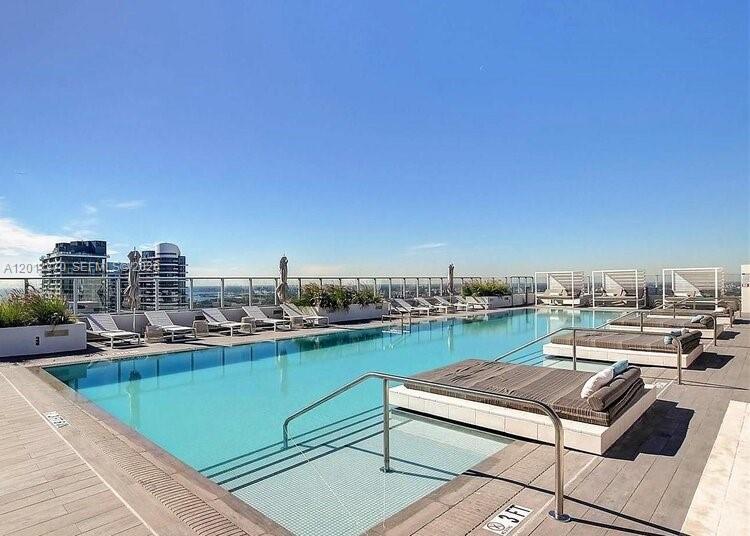 A rooftop swimming pool features lounge chairs on a wooden deck with city views — 1010 Brickell Ave # 1910, Miami FL 33131, MIAMI, FL