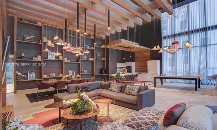 A modern living room features high ceilings, wood beams, hanging pendant lights, and built-in shelving — 1010 Brickell Ave # 1910, Miami FL 33131, MIAMI, FL