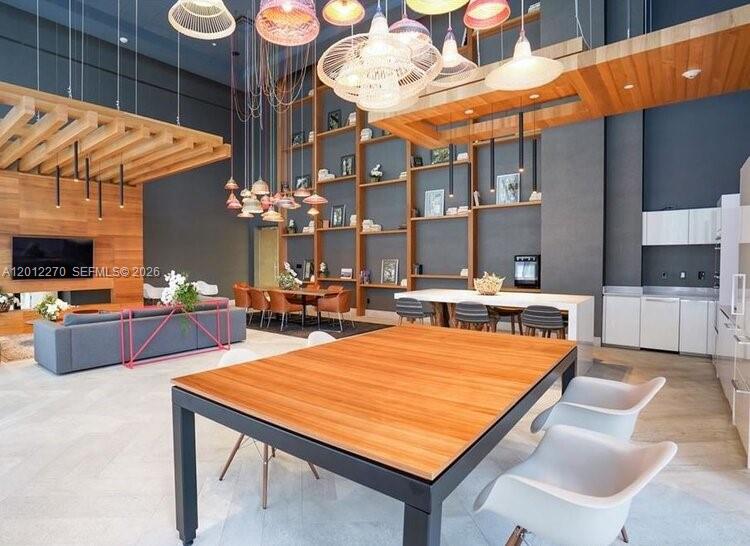 A modern open-concept living and dining area features high ceilings, wood accents, and pendant lighting — 1010 Brickell Ave # 1910, Miami FL 33131, MIAMI, FL