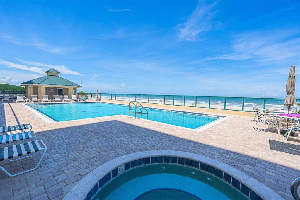 A swimming pool and hot tub overlook the ocean from a paved pool deck — 4575 S ATLANTIC AVENUE UNIT 6209, PONCE INLET, FL