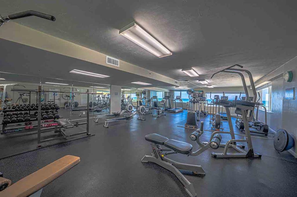 A fitness center features various exercise machines, a weight rack, mirrored walls, and ocean views — 4575 S ATLANTIC AVENUE UNIT 6209, PONCE INLET, FL