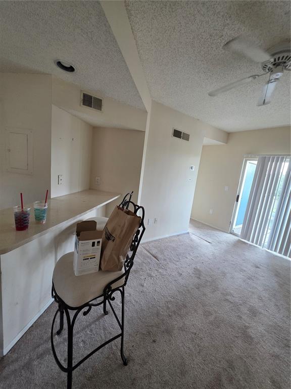 A carpeted living area features a breakfast bar with stools and a sliding glass door — 115 112TH AVENUE NE UNIT 1024, ST PETERSBURG, FL