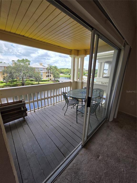 A balcony with a table and chairs overlooks a lake and neighboring apartment buildings — 115 112TH AVENUE NE UNIT 1024, ST PETERSBURG, FL