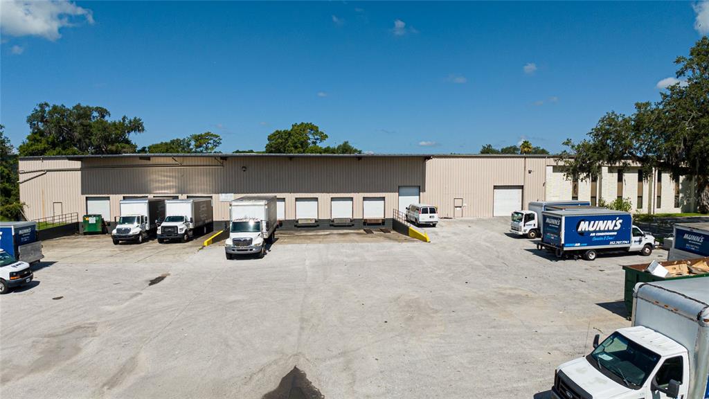 An exterior view of a commercial warehouse building with multiple loading docks and parked trucks — 3601 PARKWAY BOULEVARD, LEESBURG, FL