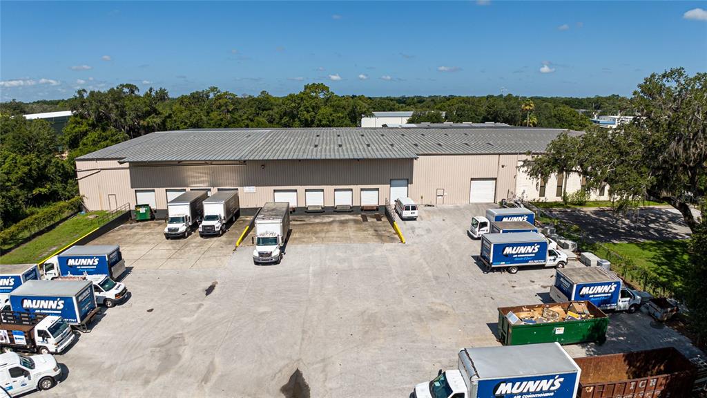 An aerial view shows a commercial warehouse building with multiple loading docks and several service trucks — 3601 PARKWAY BOULEVARD, LEESBURG, FL