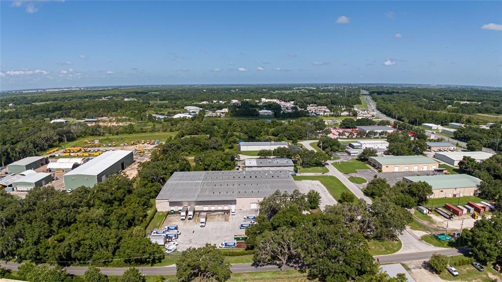 An aerial view shows a large industrial warehouse complex surrounded by trees and paved lots — 3601 PARKWAY BOULEVARD, LEESBURG, FL