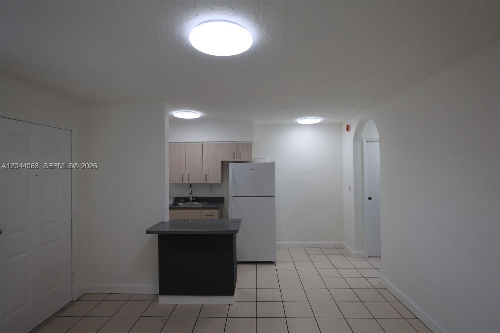 A kitchen features light wood cabinets, a white refrigerator, and a dark breakfast bar — 1235 W 66th St # 13, Hialeah FL 33012, HIALEAH, FL