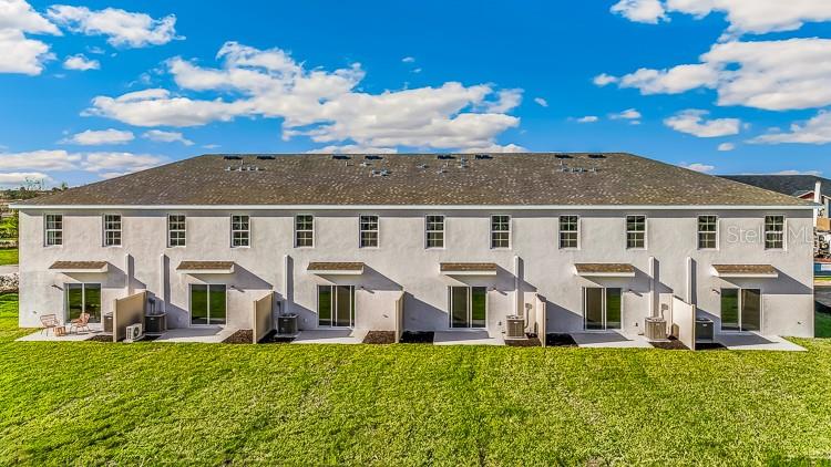 An exterior view of the rear of a multi-unit townhouse building with a grassy lawn — 10698 TIGER LILY DRIVE, VENICE, FL
