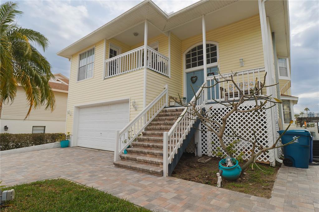 A yellow two-story house with a white garage, front staircase, and a paved driveway — 6244 SPOONBILL DRIVE, NEW PORT RICHEY, FL