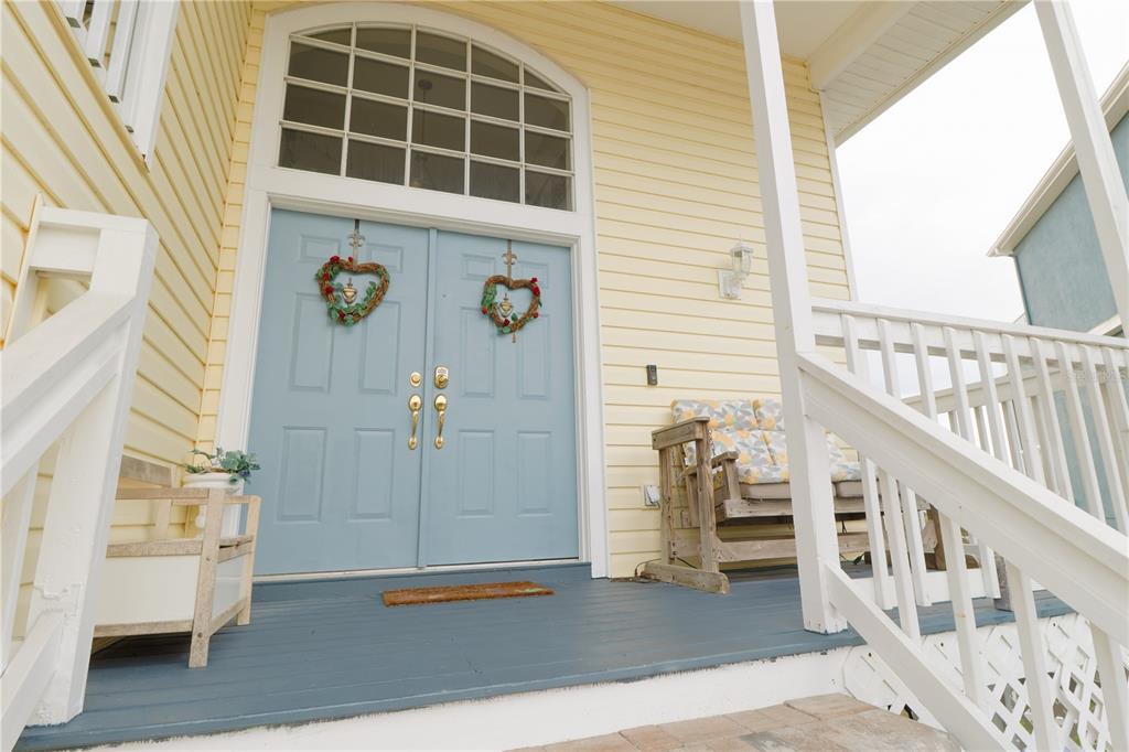 A light blue double front door with heart wreaths sits on a porch with stairs — 6244 SPOONBILL DRIVE, NEW PORT RICHEY, FL