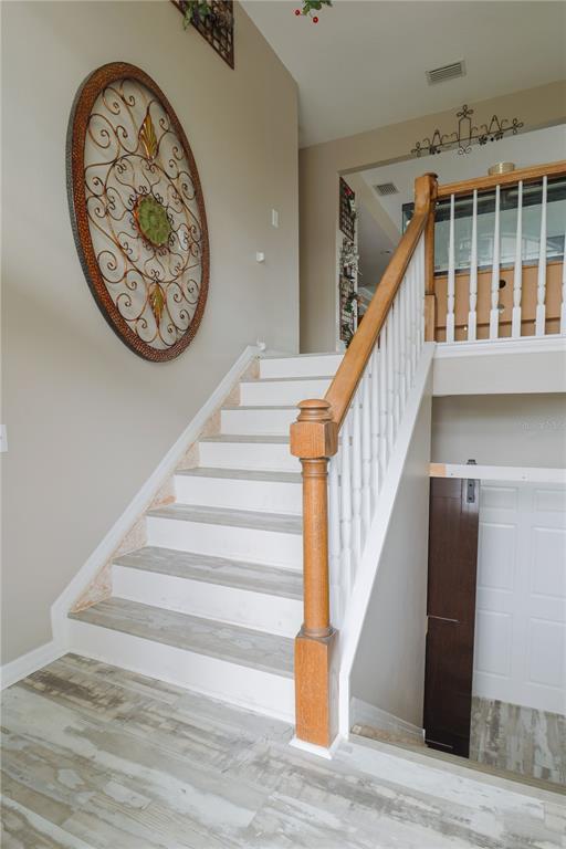 A staircase with wood railings and light-colored treads leads to an upper landing — 6244 SPOONBILL DRIVE, NEW PORT RICHEY, FL