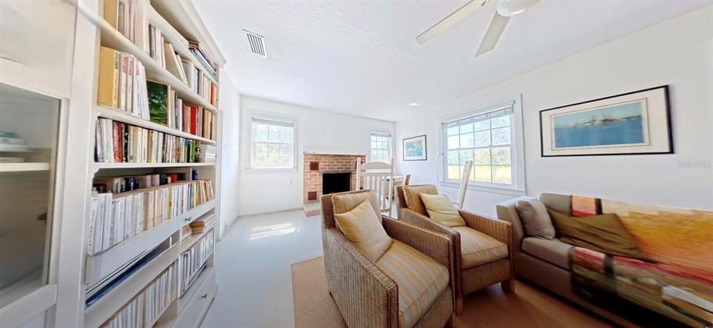 A living room features a brick fireplace, a large bookshelf, two wicker chairs, and seating — 7390 180TH STREET, MC ALPIN, FL