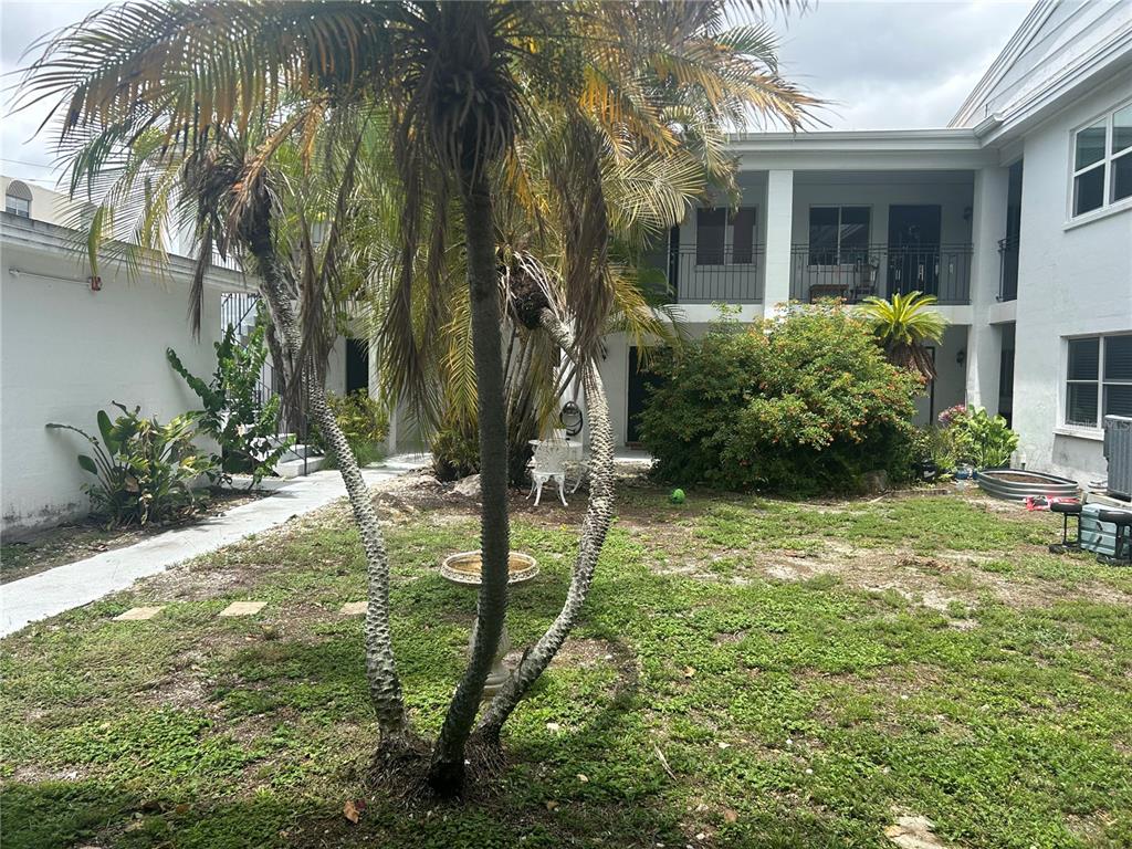 A courtyard features a palm tree, a small birdbath, and a two-story white building — 300 35TH AVENUE N UNIT F8, ST PETERSBURG, FL