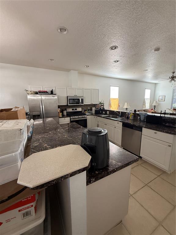 A kitchen features white cabinetry, dark granite countertops, stainless steel appliances, and tile flooring — 3201 SUMMER CRUISE DRIVE, VALRICO, FL