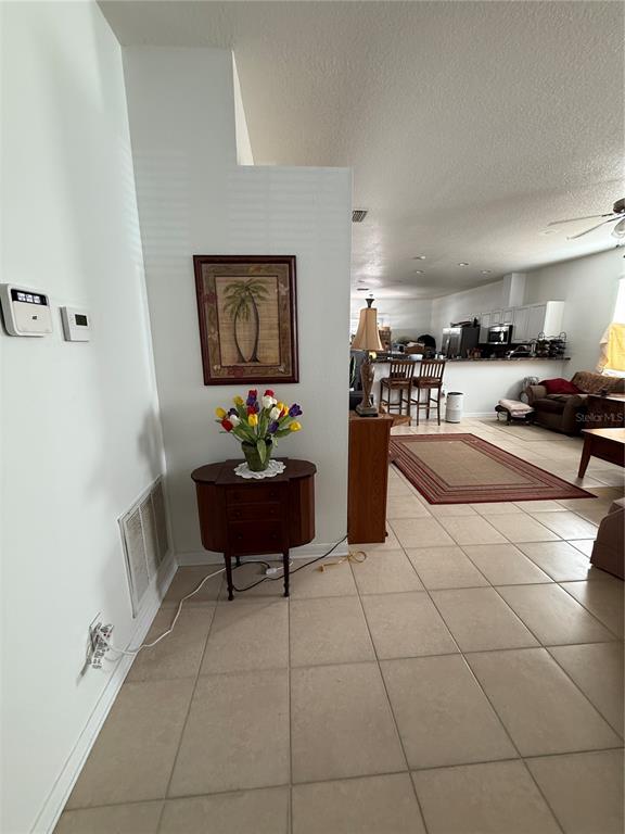 A tiled living area features a small wooden cabinet, a floral arrangement, and a wall painting — 3201 SUMMER CRUISE DRIVE, VALRICO, FL