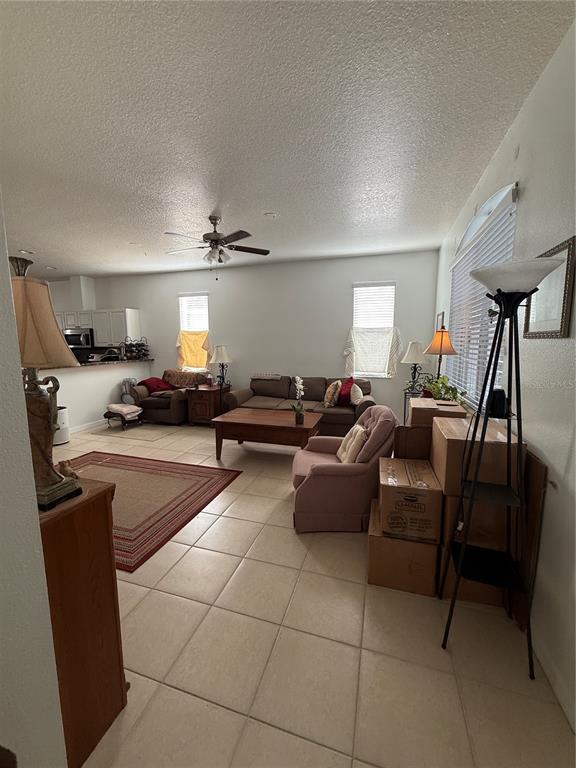 A living room with tile floors, a ceiling fan, and furniture arranged near a kitchen — 3201 SUMMER CRUISE DRIVE, VALRICO, FL