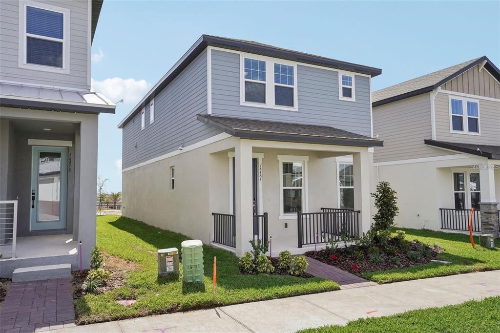 A two-story house with light blue siding, a front porch, and a small landscaped yard — 16484 SILVER BROOK WAY, WINTER GARDEN, FL